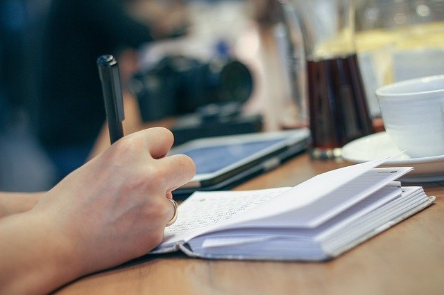 woman writing in a notebook, focus on hands