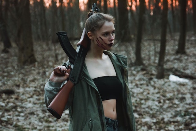 woman in woods with AK-47