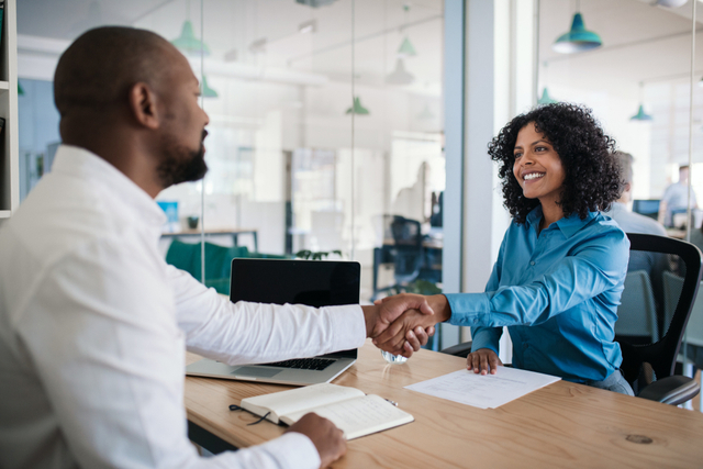 man and woman shaking hands at meeting